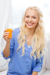 smiling woman with glass of orange juice at home