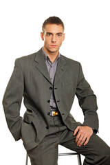 Young businessman standing at gray suit sits on chair
