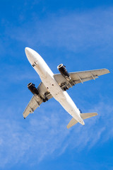 Fototapeta na wymiar Airplane Flying Overhead with Blue Sky