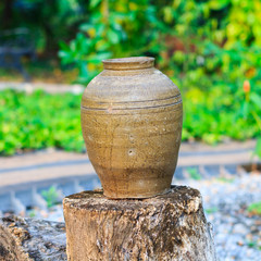 Fototapeta na wymiar Antique jar on the old log