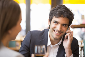 Young couple in restaurant, man is on the phone