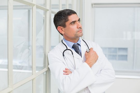 Thoughtful male doctor looking away in hospital