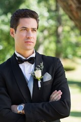 Thoughtful groom with arms crossed in garden