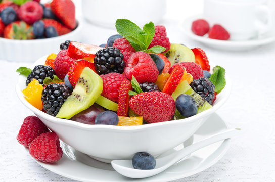 Fototapeta salad of fresh fruit and berries in a white bowl, berries