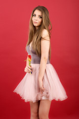 Teenage girl posing with tulip in hands on red background