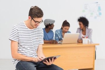 Artist using digital tablet with colleagues in background at