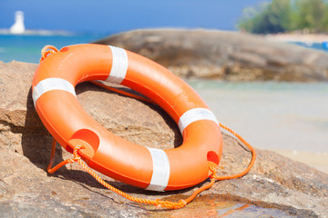 Orange lifebuoy on rocks at sea side. lifesaving equipment.