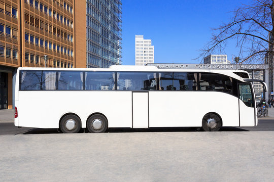 Weisser Reisebus vor Stadt-Skyline