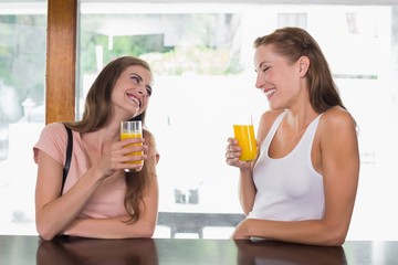 Happy friends drinking orange juice at café