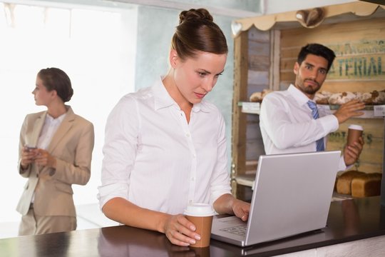 Businesswoman using laptop in office cafeteria