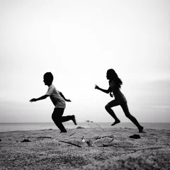 Foto op Plexiglas two kids running silhouettes running on the beach © nasruleffendy
