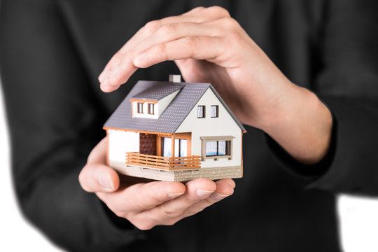 Home Insurance and protection concept. Home in man's hand