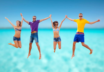 group of friends or couples jumping on the beach