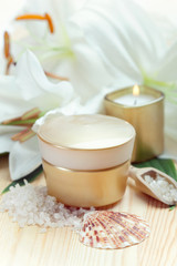 Fototapeta na wymiar Moisturizing face cream with candle and white lilies