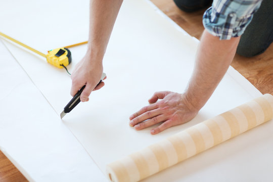 close up of male hands cutting wallpaper