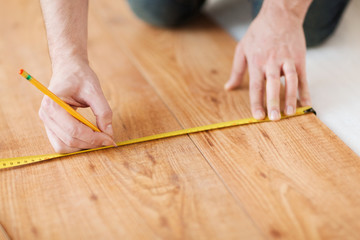 close up of male hands measuring wood flooring