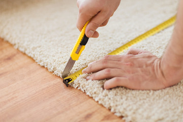 close up of male hands cutting carpet