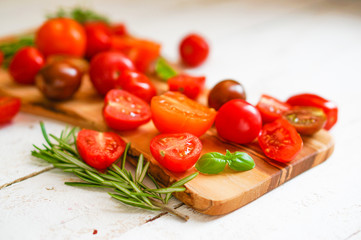 Colorful tomatoes on board on wooden background