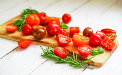 Colorful tomatoes on board on wooden background