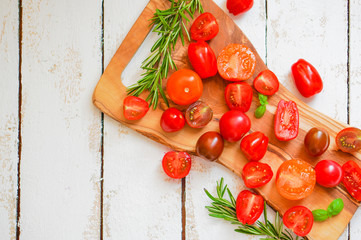 Colorful tomatoes on board on wooden background