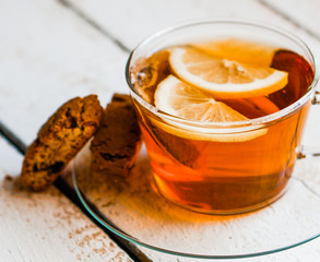 Tea cup with lemon and cookies on rustic wooden background