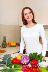 happy young woman with vegetables at kitchen