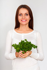 beautiful girl holding two bunches of parsley near the face