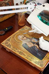 restoration of ancient gilded icon with  filling knife