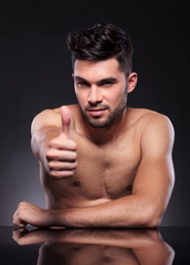 naked young man shows thumbs up