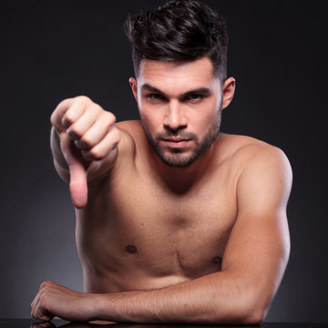 naked young man shows thumb down