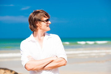 young handsome man smiling and looking in sunglasses and white