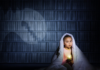 girl under the covers with a flashlight
