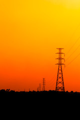 High voltage power pole middle of a cornfield with orange sky