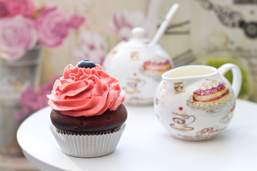 Chocolate cupcakes with pink frosting and blueberries with elegant sausepan on the background