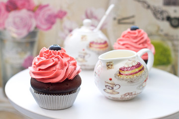 Chocolate cupcakes with pink frosting and blueberries with elegant sausepan on the background