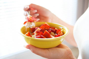 Woman holding fresh strawberries in a bowl