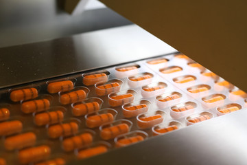 Orange capsules packed in tablet packing machine