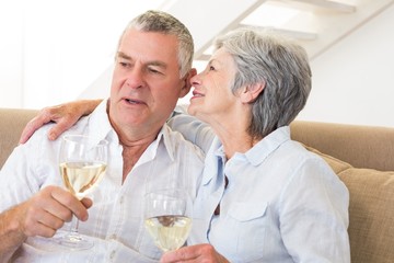 Senior couple sitting on couch drinking white wine