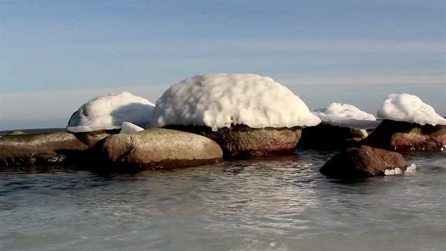 Rocks on the beach with snow caps