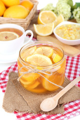 Tasty lemon jam with cup of tea on table close-up