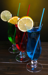 Glasses of cocktails on table on dark yellow background