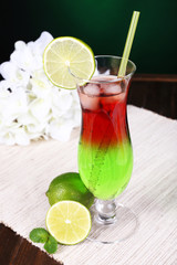 Glass of cocktail on table on dark green background