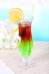 Glass of cocktail on table on light blue background