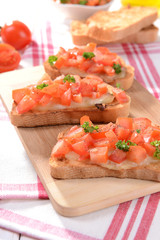 Delicious bruschetta with tomatoes on cutting board close-up