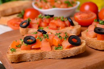 Delicious bruschetta with tomatoes on cutting board close-up