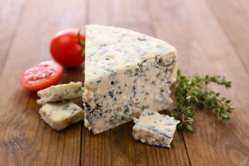 Tasty blue cheese with thyme and tomato, on wooden table