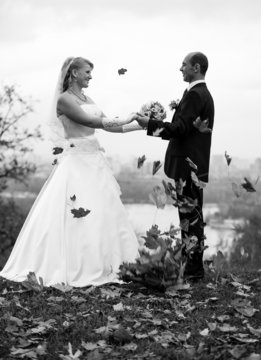 Black and white photo of bride and groom dancing at autumn park