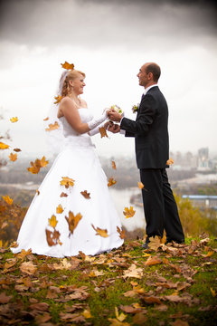 Just married couple holding hands at autumn windy day