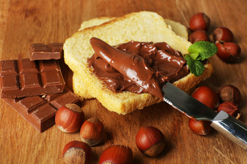 Bread with sweet chocolate hazelnut spread on wooden background