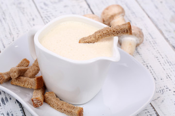 Delicate mushroom sauce in pitcher on wooden table close-up